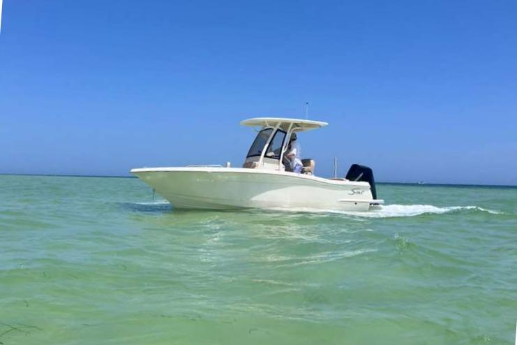 Scout 215 XSF 2025 Scout 215 XSF boat cruising on clear blue water under a sunny sky.