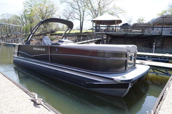 Premier 250 Sunsation 2024 Premier 250 Sunsation pontoon boat docked on a calm lake.
