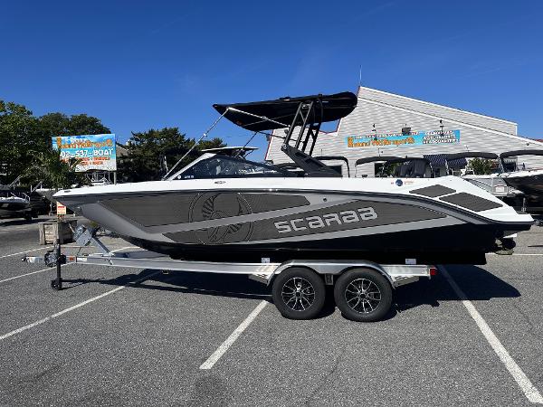 Scarab 235 LX 2025 Scarab 235 LX boat on trailer in parking lot, sunny day.