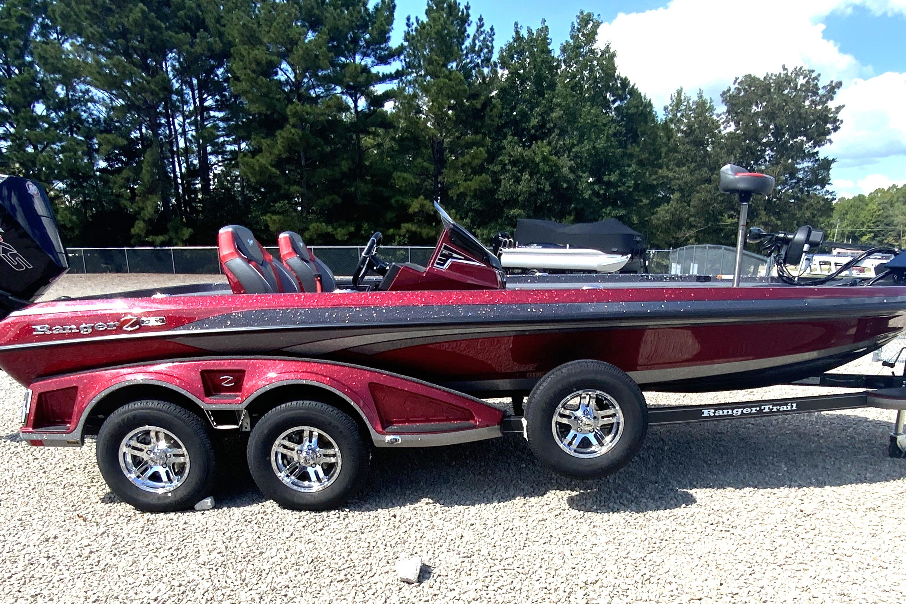 Ranger Z521R 2025 Ranger Z521R boat with dual-axle trailer, parked on gravel, surrounded by trees.