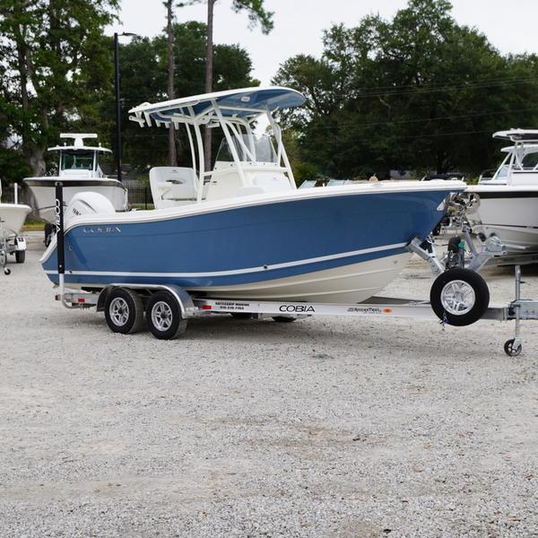 Cobia 220 Center Console 2025 Cobia 220 Center Console boat on trailer, blue hull, parked outdoors.