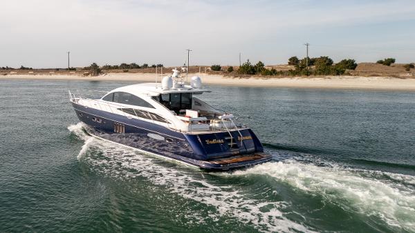 Princess V65 2006 Princess V65 yacht cruising near a sandy shoreline.