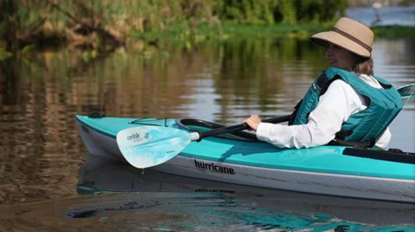 Hurricane Kayaks Prima 110 Sport Person kayaking in a 2023 Hurricane Kayaks Prima 110 Sport on a calm river.