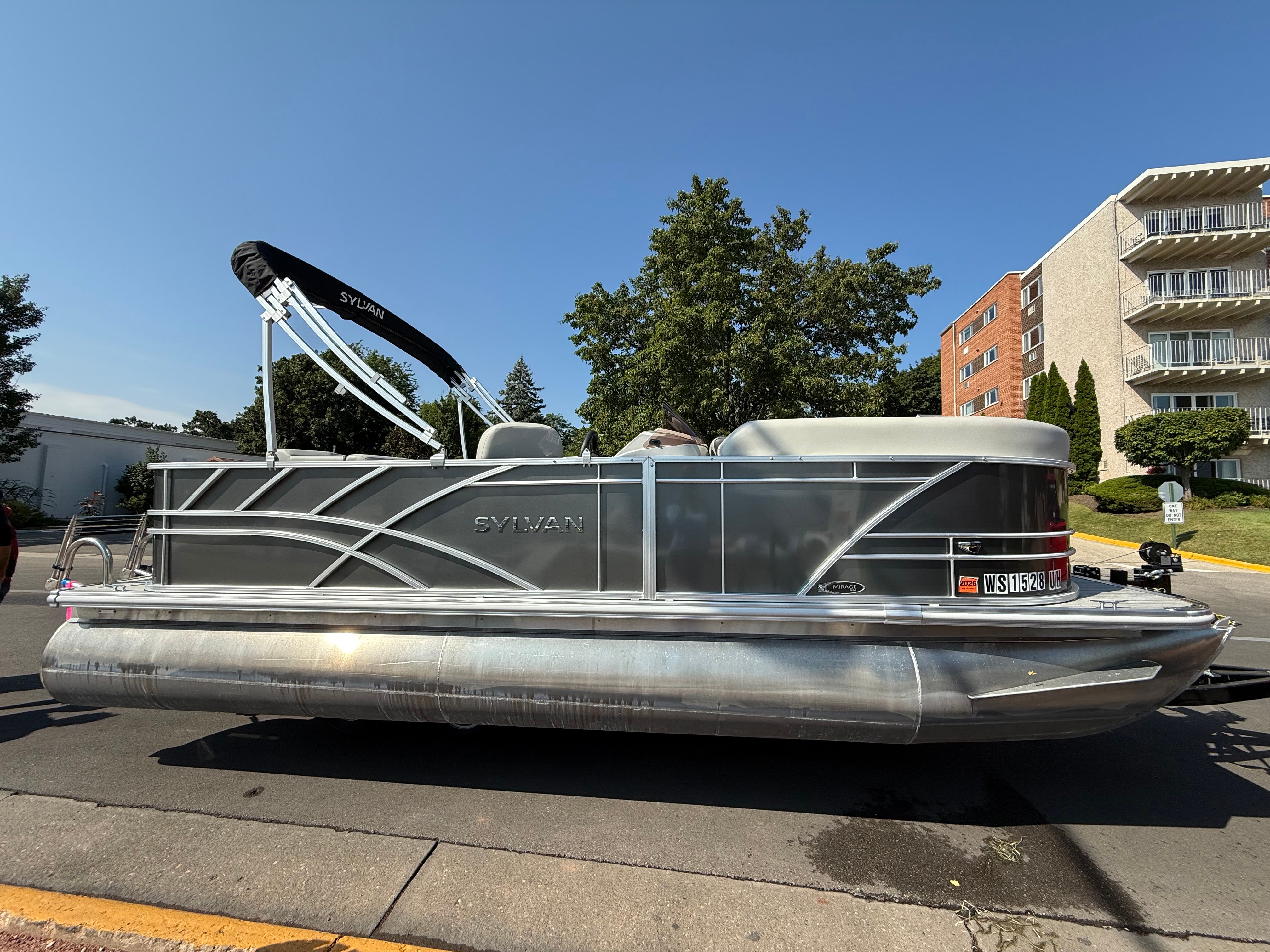 Sylvan Mirage 2023 Sylvan Mirage pontoon boat parked on a street, sunny day.