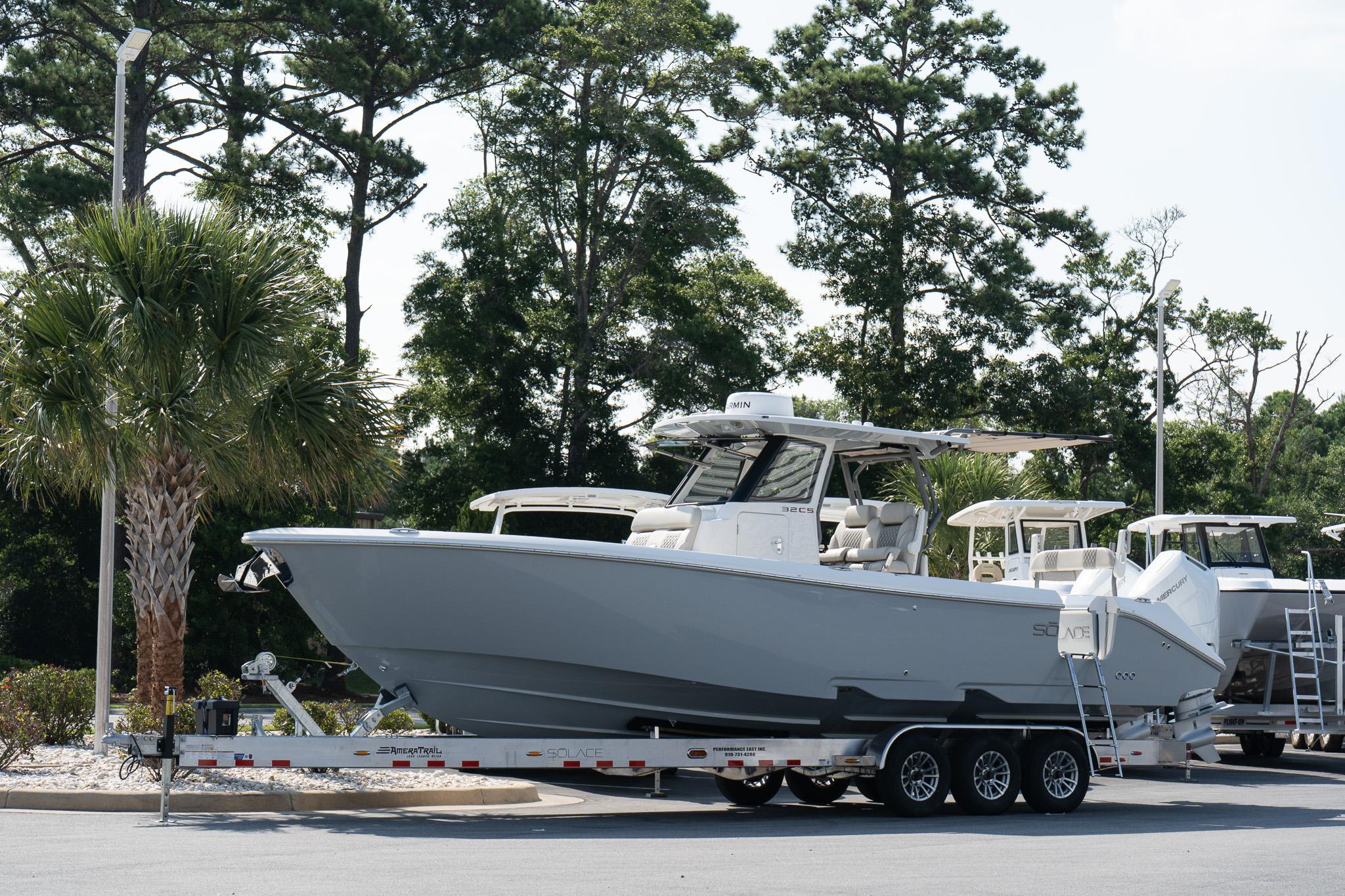 Solace 32 CS 2025 Solace 32 CS boat on trailer, surrounded by trees and parked outdoors.