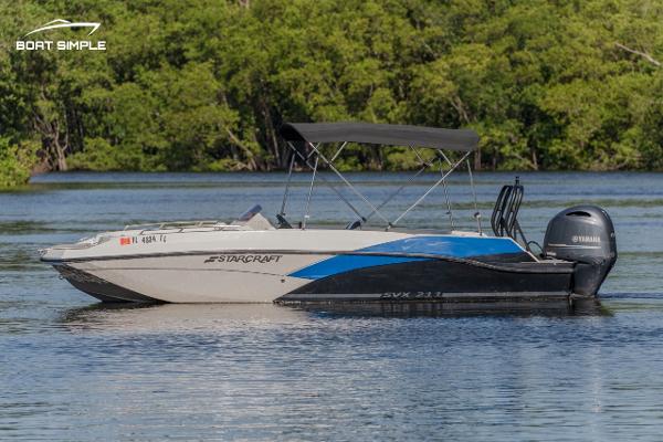 Starcraft SVX 211 OB 2023 Starcraft SVX 211 OB boat on a calm lake with lush green background.