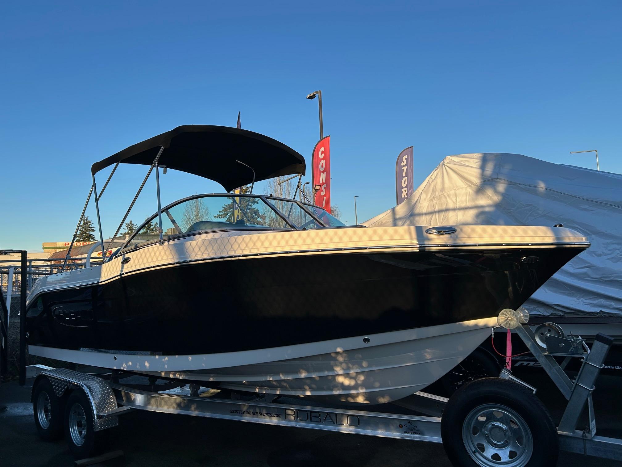 Robalo R207 Dual Console 2026 Robalo R207 Dual Console boat on trailer, under clear blue sky.