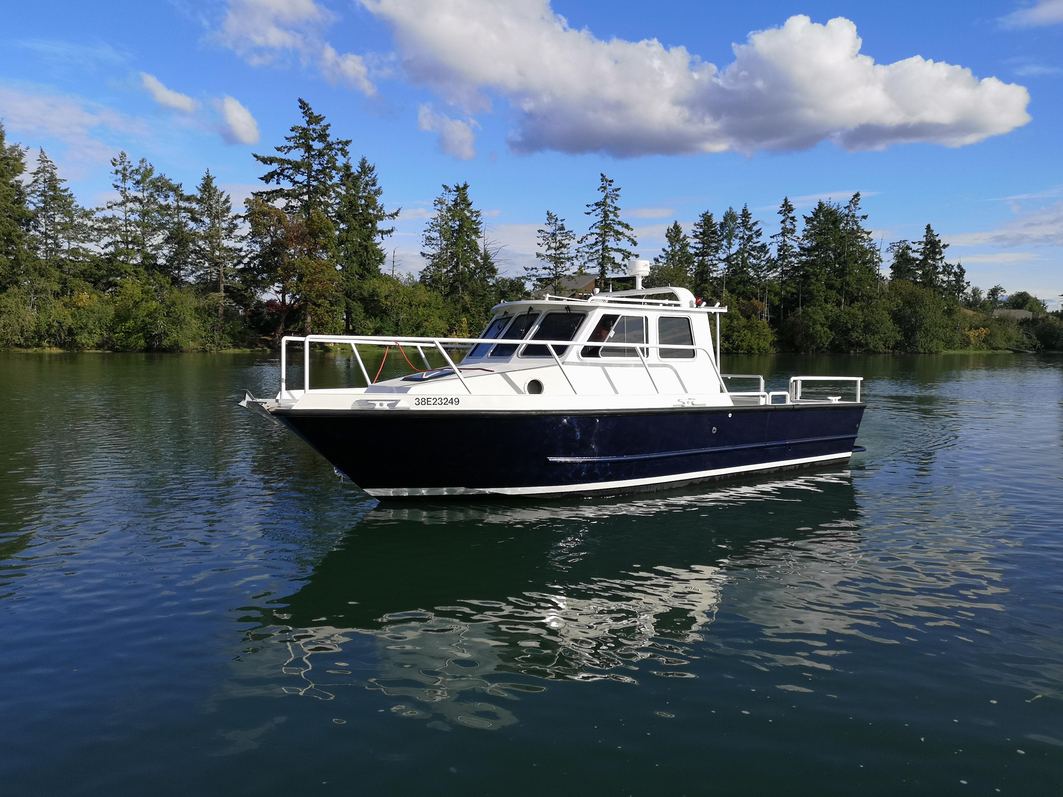 Custom Hike Aluminium 30 Custom Hike Aluminium 30 boat from 1999 on a serene lake with trees and clouds.