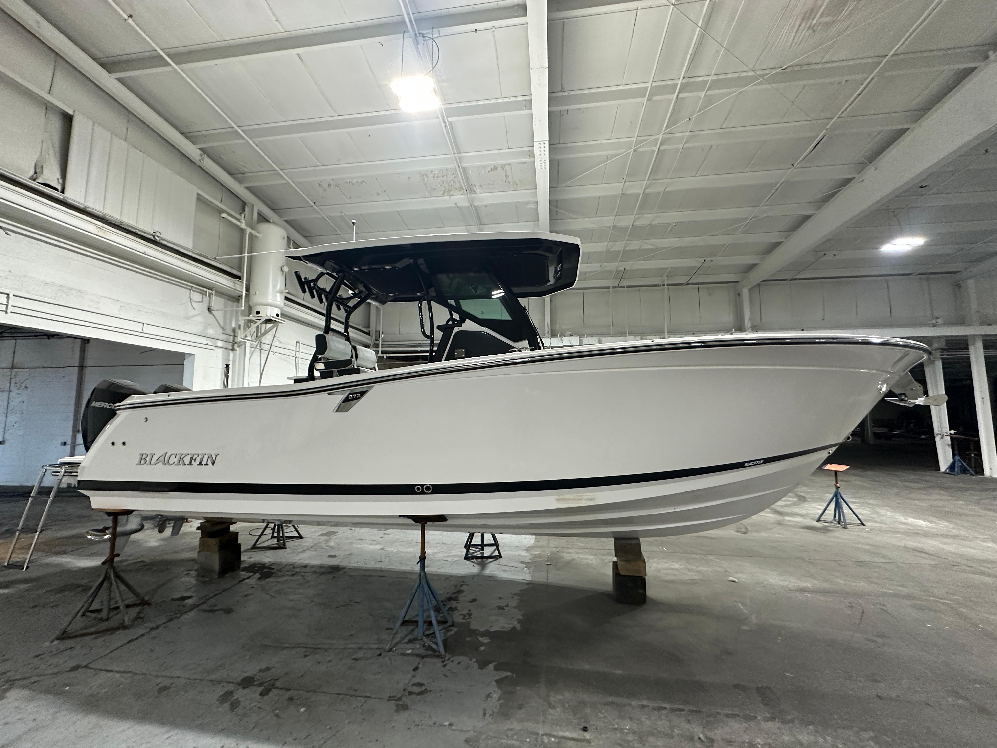 Blackfin 272CC 2025 Blackfin 272CC boat in a warehouse, side view.