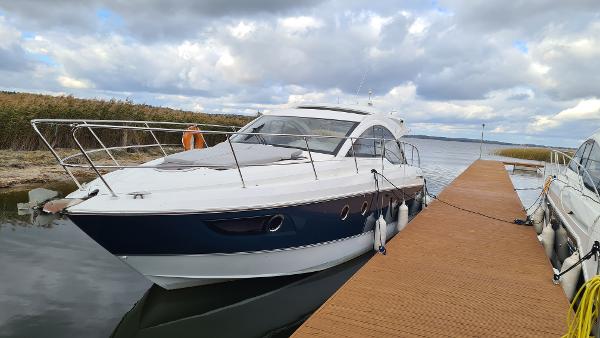 Beneteau GRAN TURISMO 38 2013 Beneteau GRAN TURISMO 38 yacht docked by a wooden pier under cloudy skies.