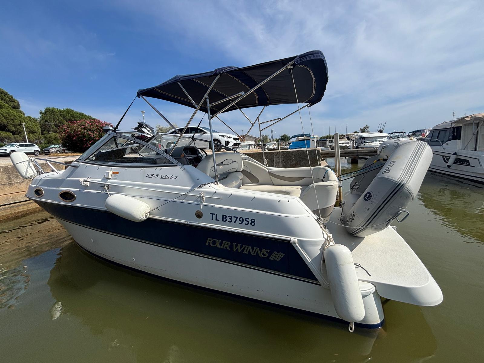 Four Winns 238 Vista 2000 Four Winns 238 Vista boat docked in a marina under a clear blue sky.