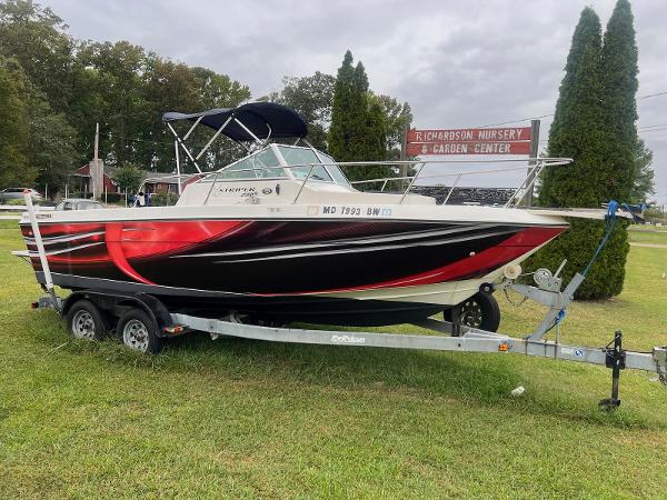 Seaswirl Striper 2150 Walkaround 1998 Seaswirl Striper 2150 Walkaround boat on trailer, parked on grass near nursery sign.