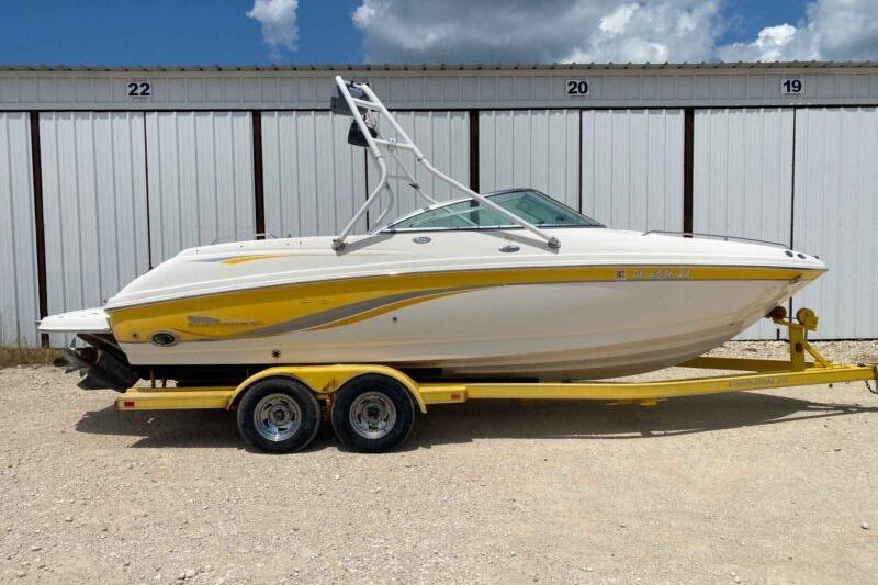 Chaparral 230 SSi 2004 Chaparral 230 SSi boat on yellow trailer, parked near storage units.