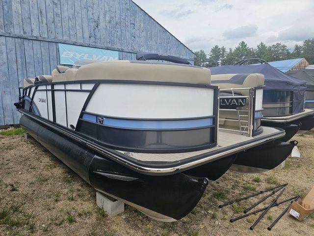 Sylvan L3 RLZ 2025 Sylvan L3 RLZ pontoon boat displayed outdoors near a blue building.