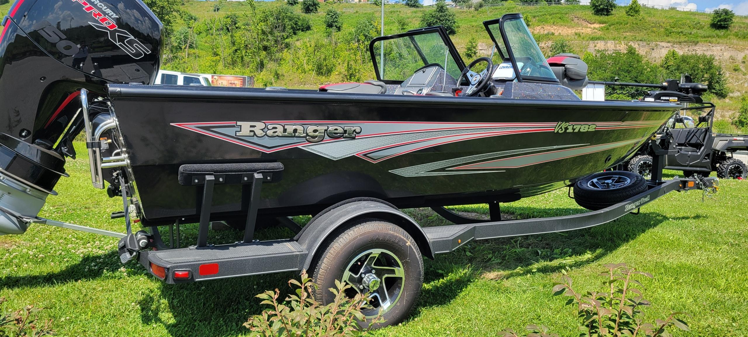 Ranger VS1782SC Reata 2024 Ranger VS1782SC Reata boat on trailer, black with red accents, parked on grass.