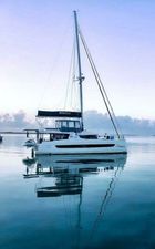 Bali catamaran Bali 2022 catamaran sailing on calm waters at sunset, reflecting in the sea.