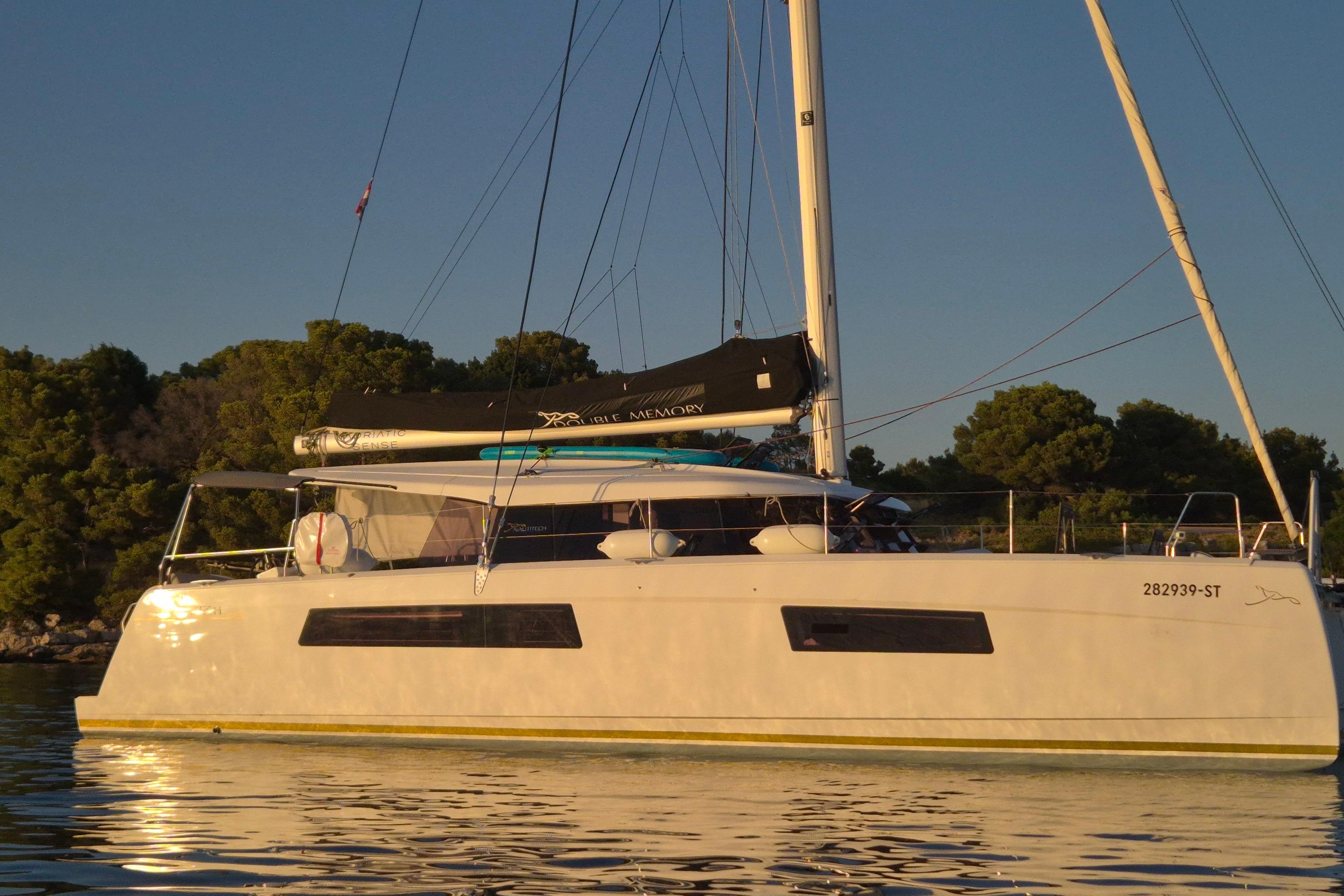 Nautitech 44 2023 Nautitech 44 catamaran anchored in calm waters at sunset.