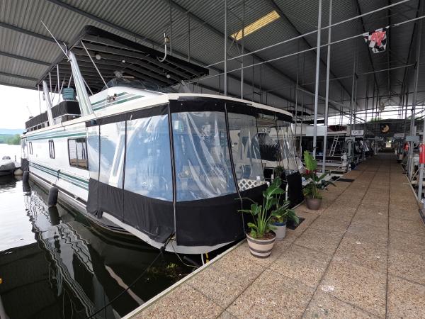 Jamestowner 1667WB Americana Custom 1998 Jamestowner 1667WB Americana Custom houseboat docked in covered marina with potted plants.