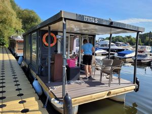 Woma Houseboat FLÖSSER D9 Motorboot 2016 Woma Houseboat FLÖSSER D9 docked, with person on deck, surrounded by other boats.