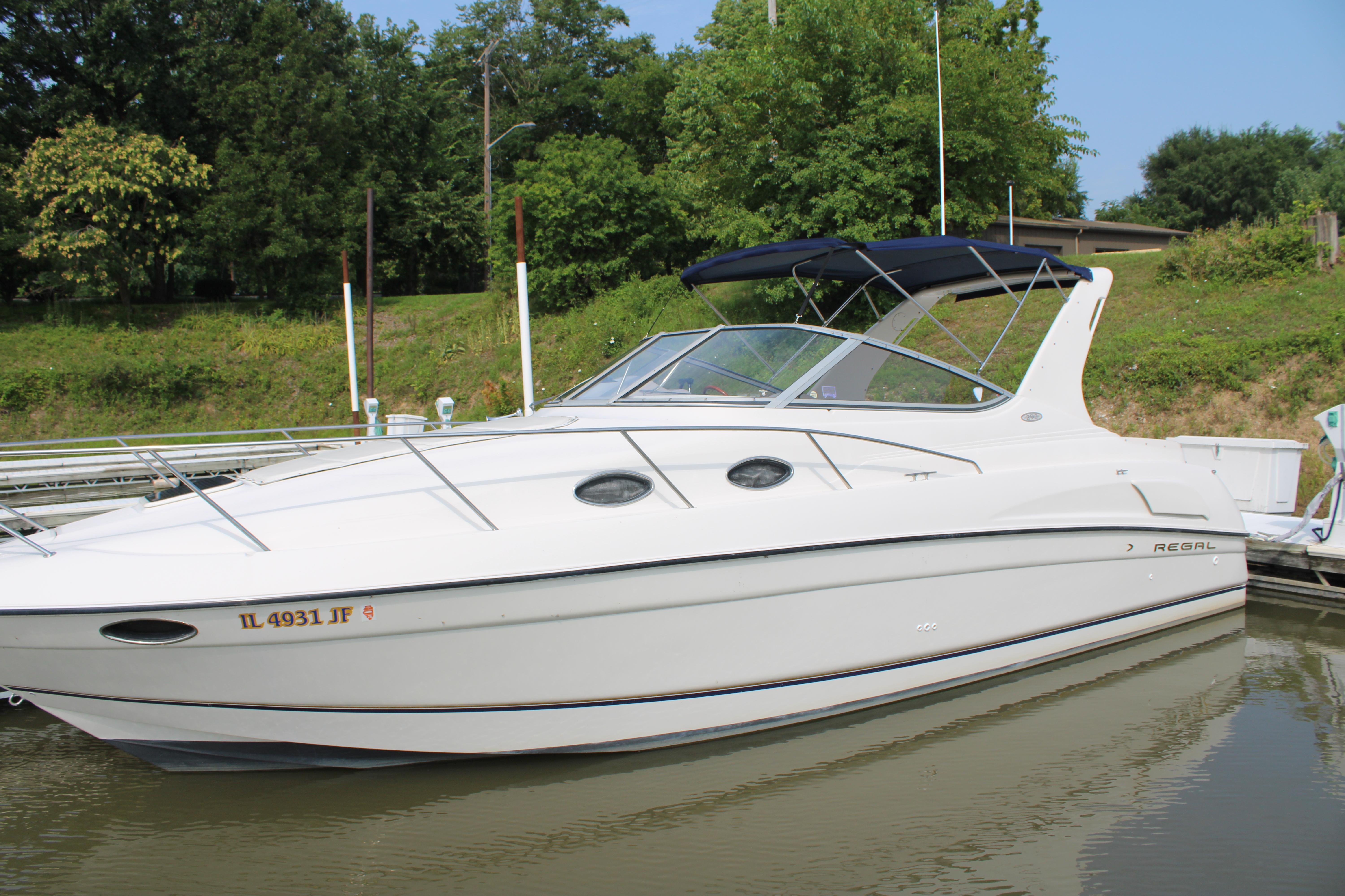 Regal 292 Commodore 1999 Regal 292 Commodore boat docked on a calm river, surrounded by lush greenery.