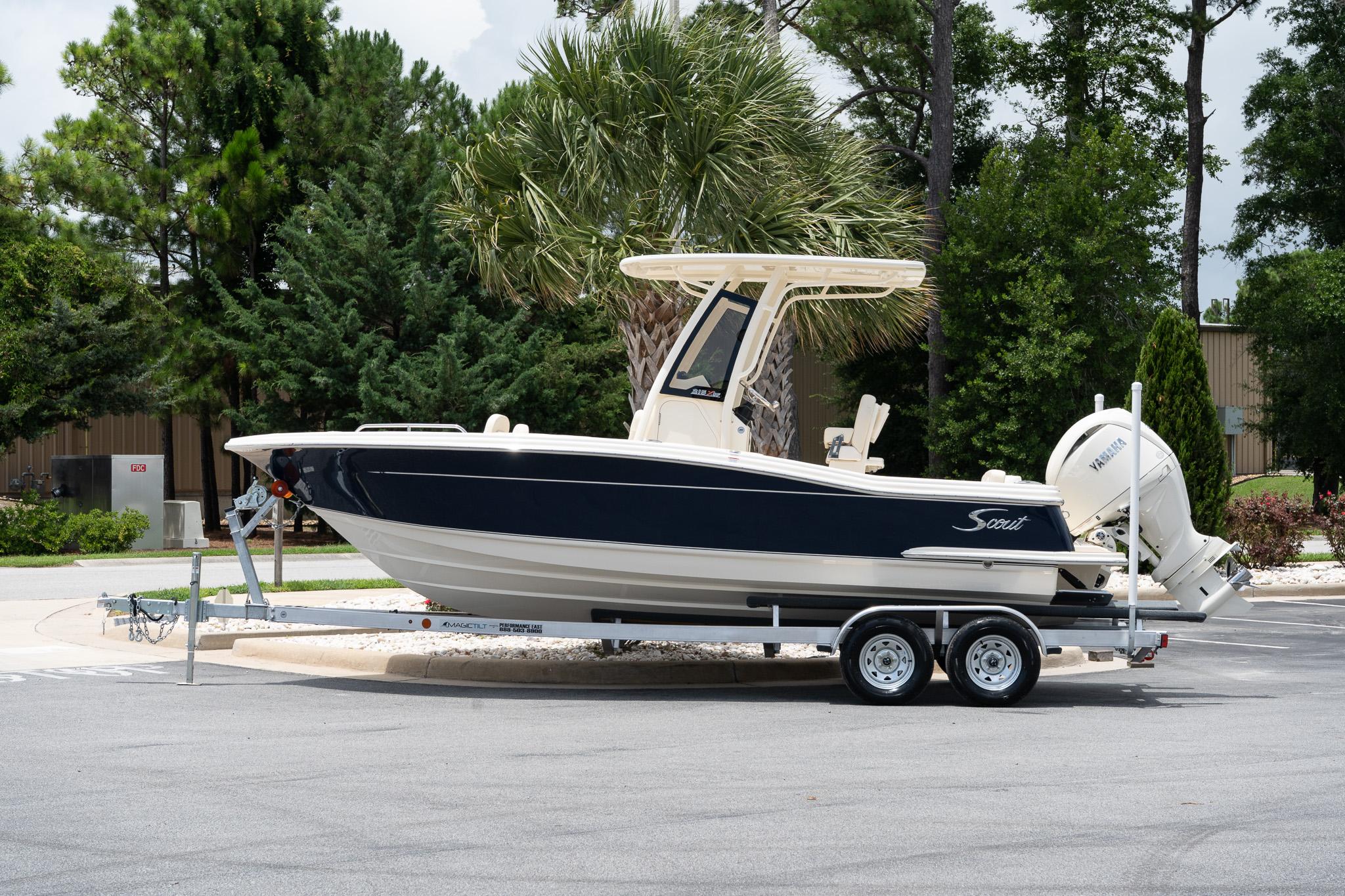 Scout 215 XSF 2026 Scout 215 XSF boat on trailer, parked outdoors with lush greenery background.