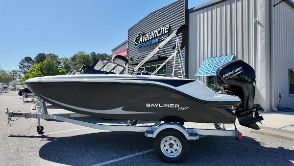 Bayliner M17 2025 Bayliner M17 boat on trailer outside dealership, featuring sleek design and Mercury outboard motor.