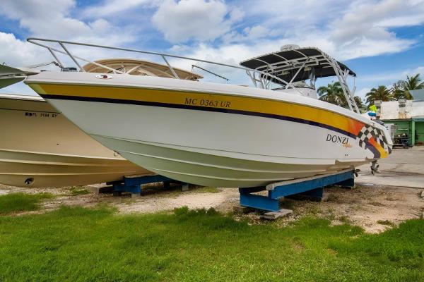 Donzi 35 ZF Cuddy 2005 Donzi 35 ZF Cuddy boat on display, white hull with yellow stripe, parked on grass.