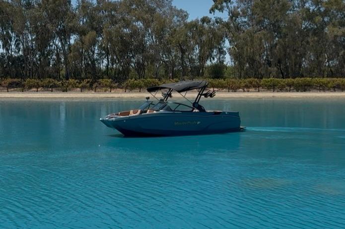 MasterCraft XT22 2025 MasterCraft XT22 boat on serene blue water, surrounded by trees.