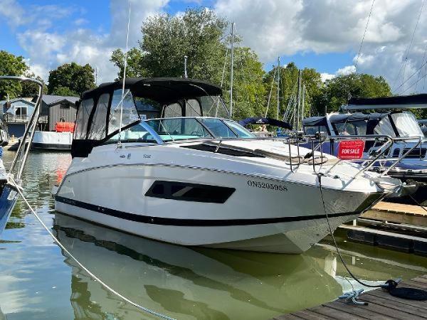 Four Winns V255 2016 Four Winns V255 boat docked, for sale, under a partly cloudy sky.