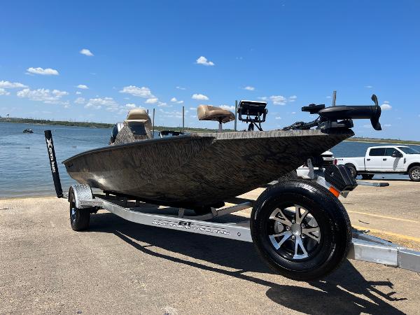 Xpress HyperLift series H17 2024 Xpress HyperLift H17 boat on trailer by the lake under clear blue sky.