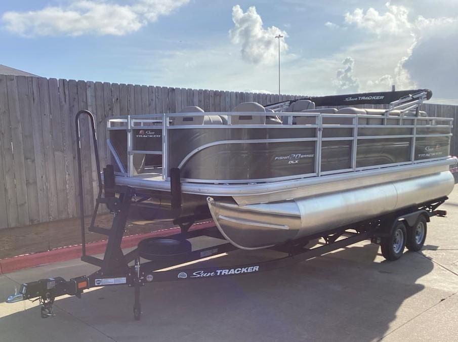 Sun Tracker Fishin' Barge 20 DLX 2025 Sun Tracker Fishin' Barge 20 DLX pontoon boat on trailer, parked outdoors.