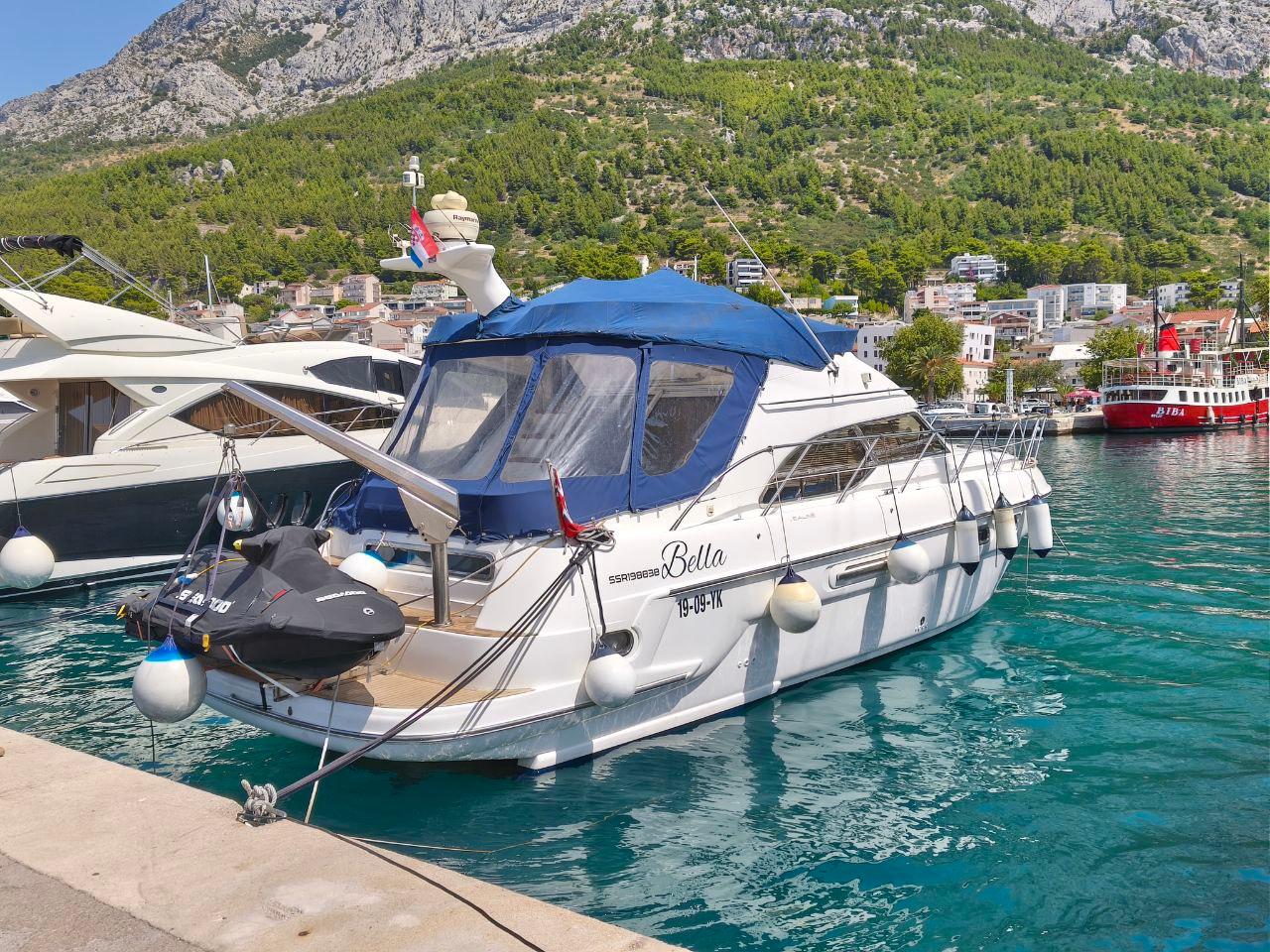 Sealine F43 2006 Sealine F43 yacht docked in a scenic marina with mountainous backdrop.
