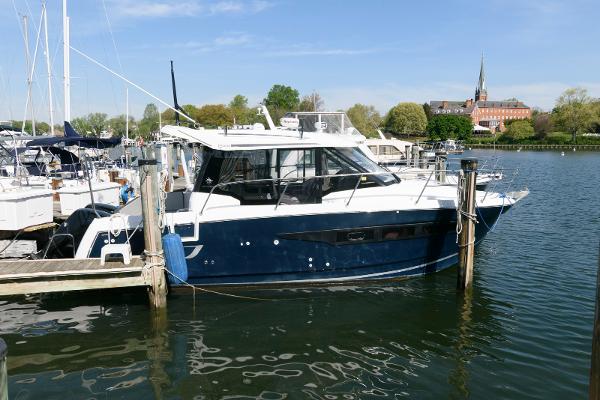 Jeanneau NC 895 2019 Jeanneau NC 895 boat docked in a marina with scenic background.