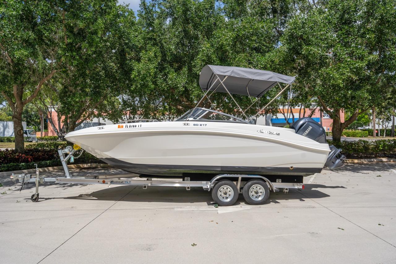 Hurricane SunDeck 217 OB 2021 Hurricane SunDeck 217 OB boat on trailer, parked outdoors with trees in background.