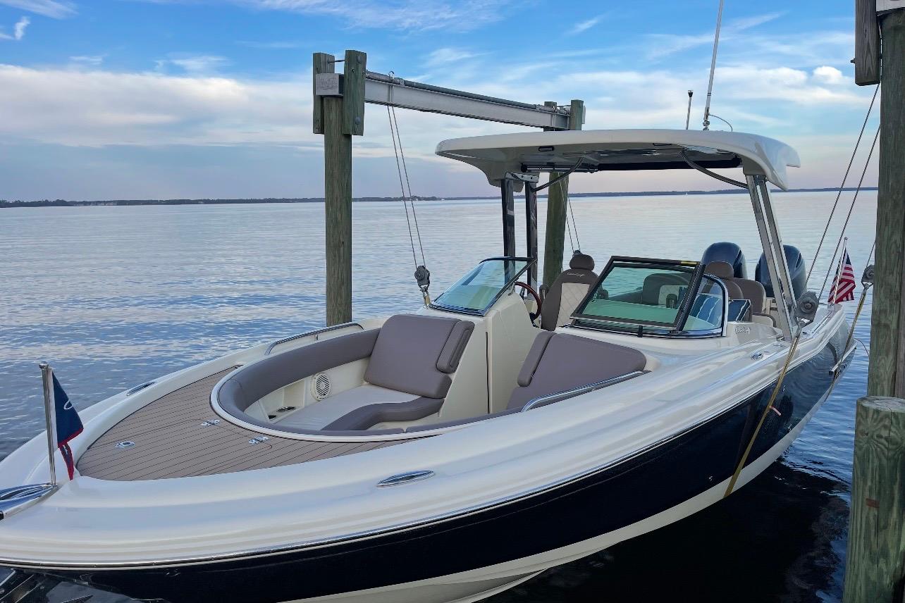 Chris-Craft Calypso 26 2019 Chris-Craft Calypso 26 boat docked by calm waters under a blue sky.