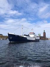 Classic Converted Icebreaker 29M Classic 1896 Converted Icebreaker 29M sailing on a calm waterway under a partly cloudy sky.