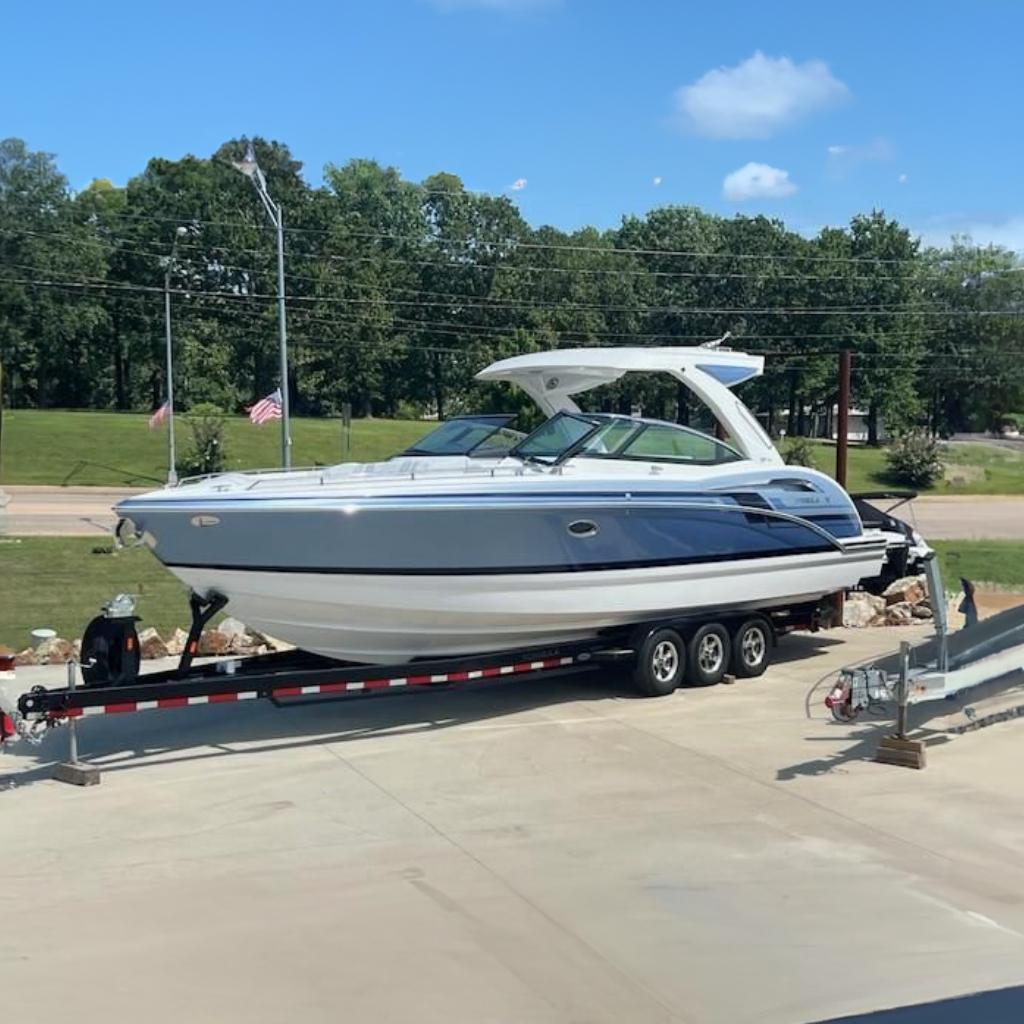Formula 350 CBR 2023 Formula 350 CBR boat on trailer, parked outdoors, with trees and flags in the background.