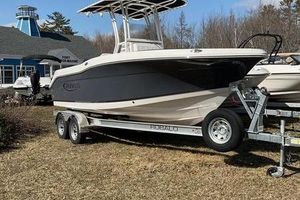 Robalo R200 Center Console 2025 Robalo 200 CC boat on trailer, parked on grass near a blue building.