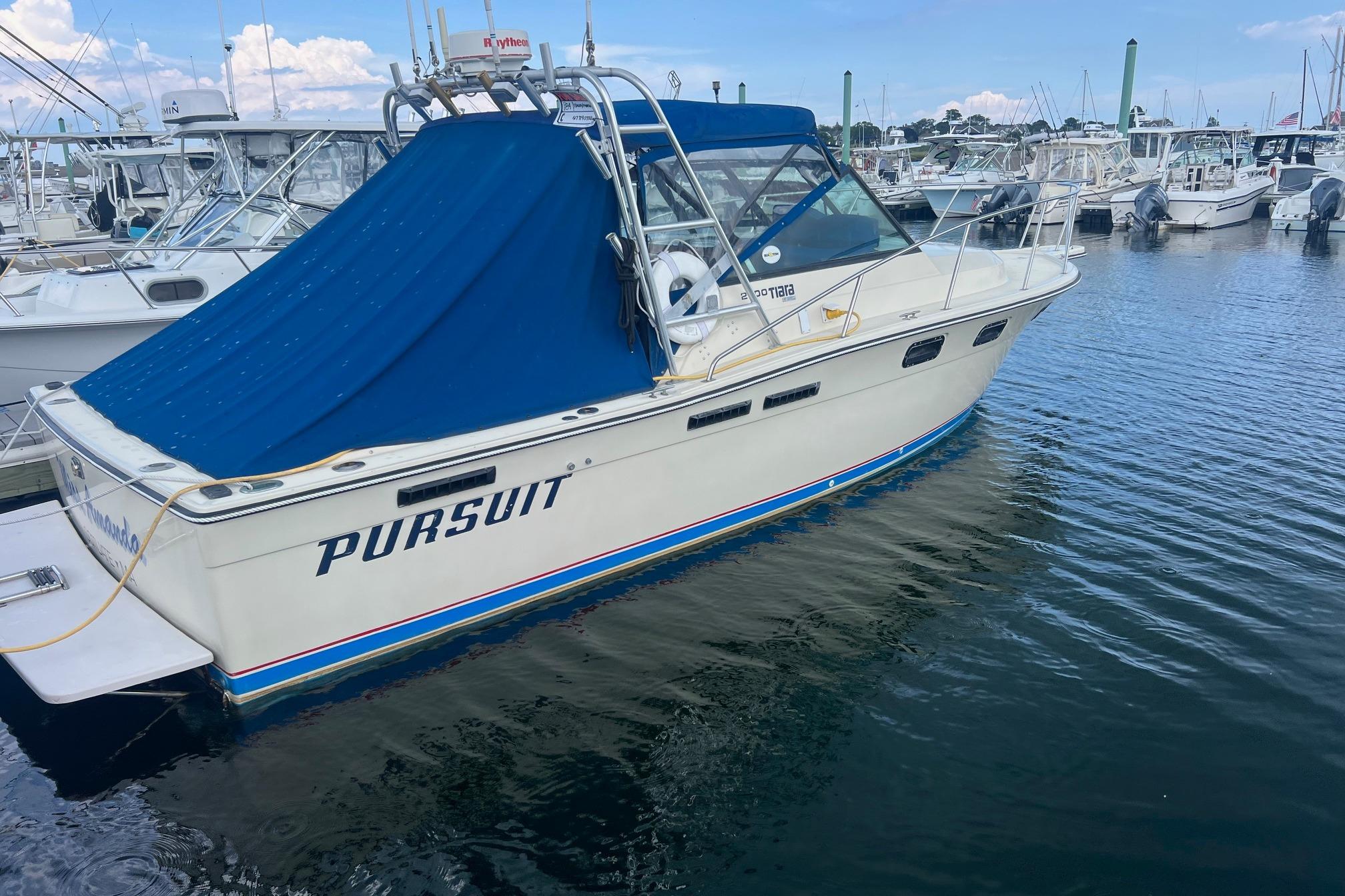 Tiara Yachts 2700 1984 Tiara 2700 boat with blue cover docked in marina, labeled "Pursuit."