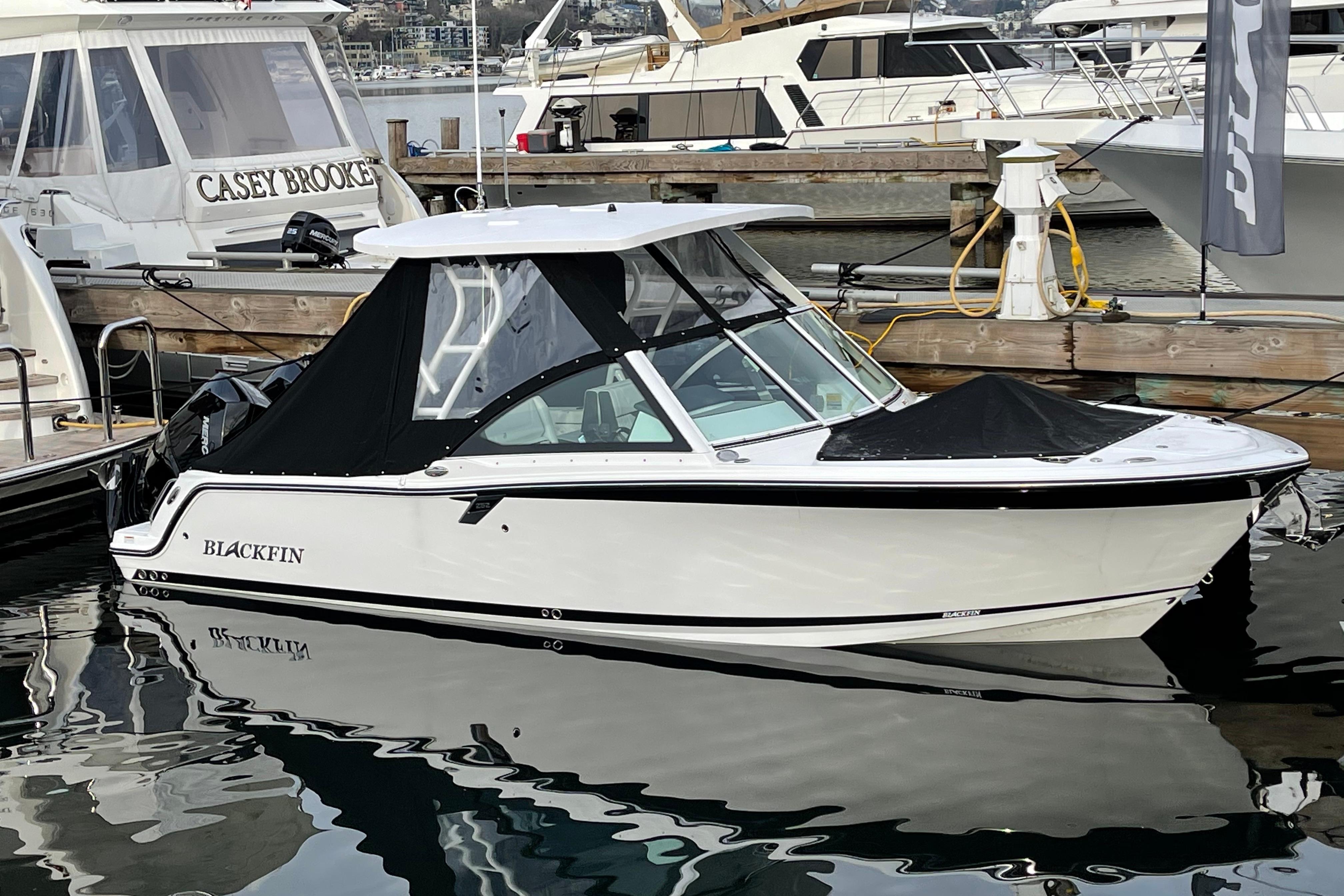 Blackfin 252DC 2021 Blackfin 252DC boat docked at marina, featuring sleek design and black canopy.