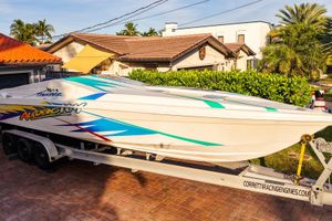 Active Thunder 32 2000 Active Thunder 32 speedboat on trailer, vibrant graphics, parked in residential driveway.