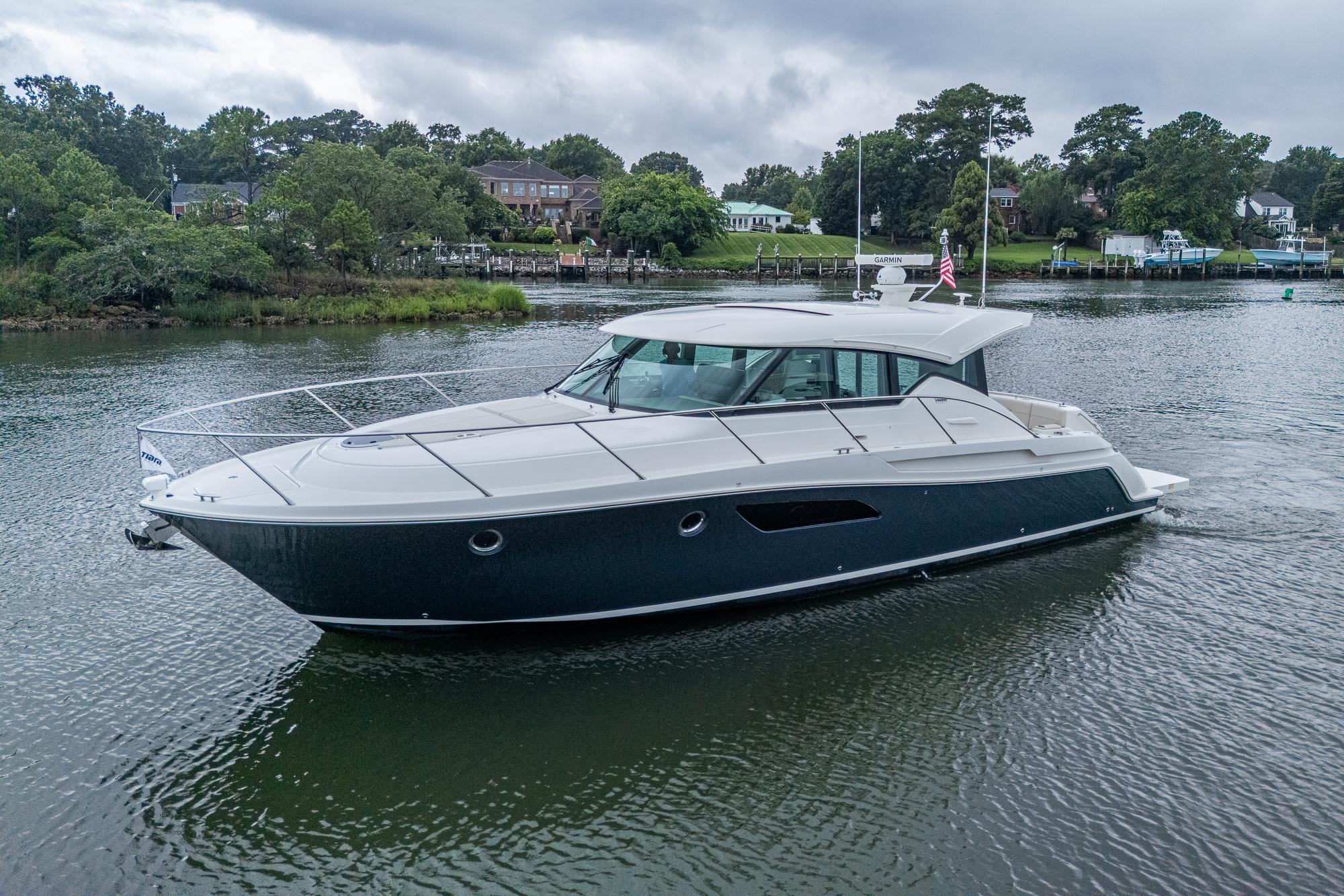 Tiara Yachts C44 Coupe 2020 Tiara Yachts C44 Coupe cruising on a serene lake with lush greenery.
