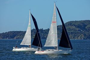 J Boats J/120 Two J Boats J/120 sailboats racing on the water, 2001 model, with scenic background.
