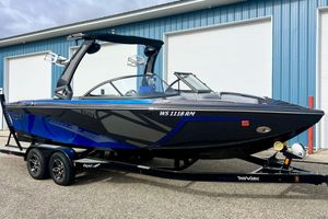 Tigé R21 2017 Tigé R21 boat with blue and black design on a trailer, parked near a blue building.