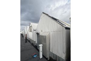 Custom Boathouse Row of custom boathouses from 1980 under cloudy sky.