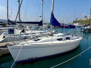 Westerly GK33 1999 Westerly GK33 sailboat docked in marina, featuring blue sail cover and sleek white hull.