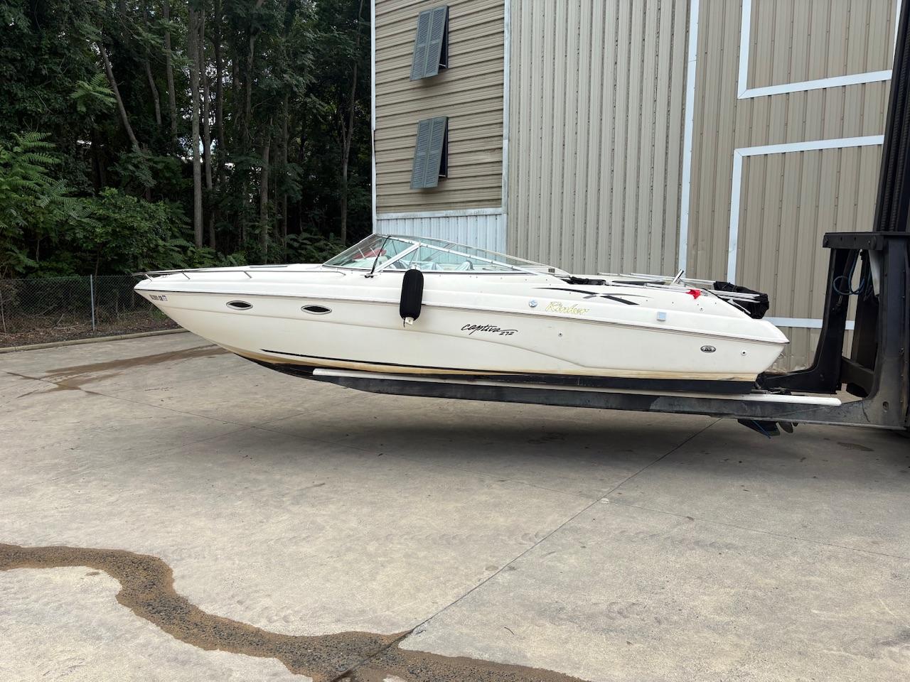 Rinker 272 Captiva Cuddy 2000 Rinker 272 Captiva Cuddy boat on forklift near building and trees.