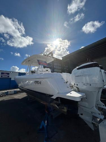 Intrepid 327 Center Console 2025 Suzuki 300hp 2018 Intrepid 327 OPEN boat with twin engines, parked outdoors under a sunny sky.