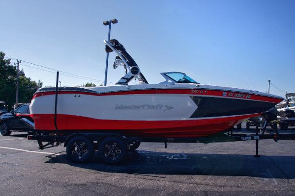MasterCraft XStar 2018 MasterCraft XStar boat with red and white design on a trailer in a parking lot.