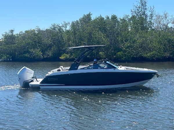 Cobalt R6 Outboard 2025 Cobalt R6 Outboard boat cruising on a sunny day near lush greenery.